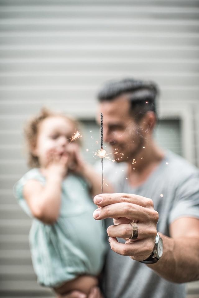 Padre con su hija en brazos celebrando el día del padre con una vengala en la mano